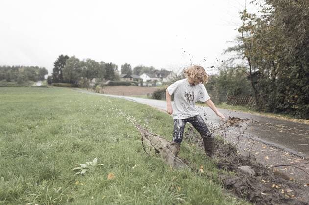 Boy jumping into a muddy puddle model released Symbolfoto  EYAF00020