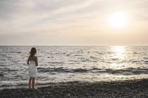 Little girl in white dress looking at sunset over the sea model released Symbolfoto  EYAF00116