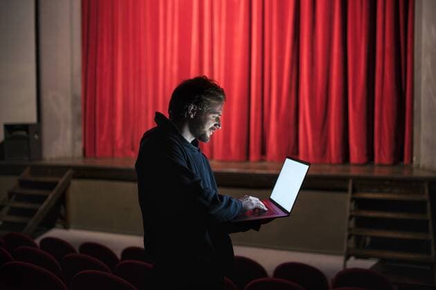Director standing at auditorium of theatre using laptop model released Symbolfoto property released  FBAF00285