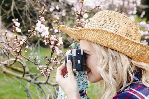 Young woman with a straw hat taking pictures in the garden with an old camera model released Symbolfoto property released  HMEF00304