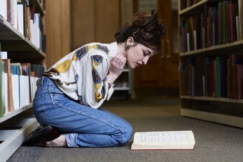 Female student reading book in a public library model released Symbolfoto  IGGF01037