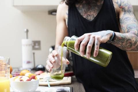Lifestyle, Haushalt, Küche, nachhaltig und plastikfrei Tattooed young man pouring in healthy smoothie in kitchen model released Symbolfoto property released  IGGF01091