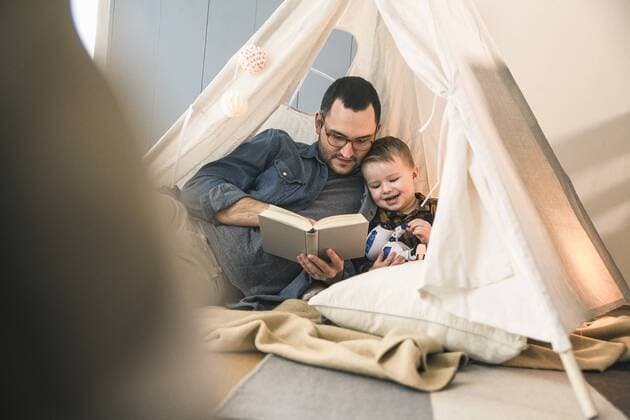Father and son reading a book together in tent at home model released Symbolfoto property released  UUF16854