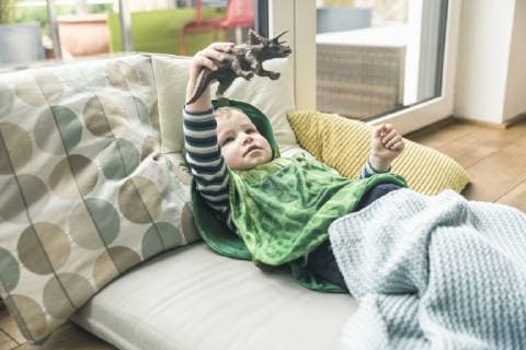 Boy in a costume lying on amattress playing with toy figure at home model released Symbolfoto property released  UUF16916
