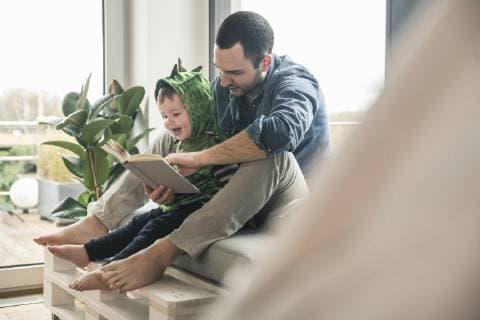 Boy in a costume with father reading book at home model released Symbolfoto property released  UUF16920