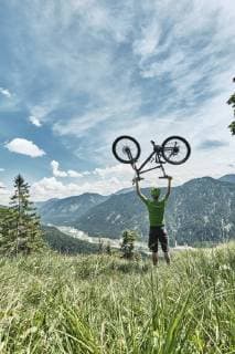 Germany, Bavaria, Isar Valley, Karwendel Mountains, mountainbiker on a trip lifting up his bike on alpine meadow model released Symbolfoto  WFF00076