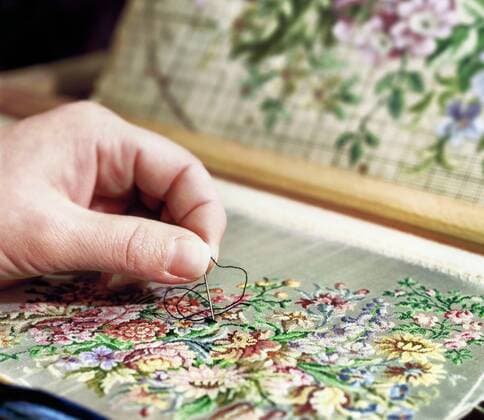 IMAGO Creative: Digitale Welt, Verzicht auf Technologie Sticken als altes Handwerk, Nahaufnahme einer Hand mit Sticknadel auf einer Stickerei mit Blumenmuster Stickarbeit *** Embroidery as an old craft, close-up of a hand with an embroidery needle on an embroidery with a floral pattern.