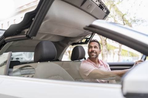 Man sitting in car with closing convertible top model released Symbolfoto  DIGF06990