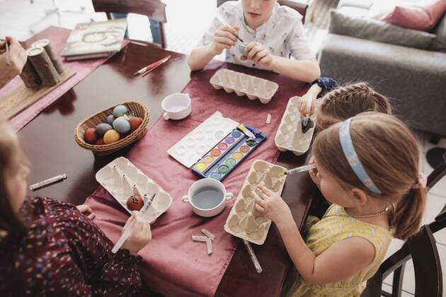 IMAGO Creative: Ostern Children painting Easter eggs on table at home model released Symbolfoto property released  KMKF00927