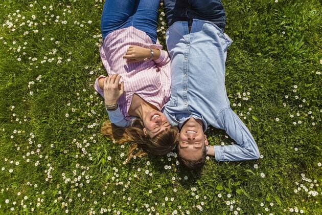 Happy young couple relaxing on grass in a park, overhead view model released Symbolfoto  MGIF00475