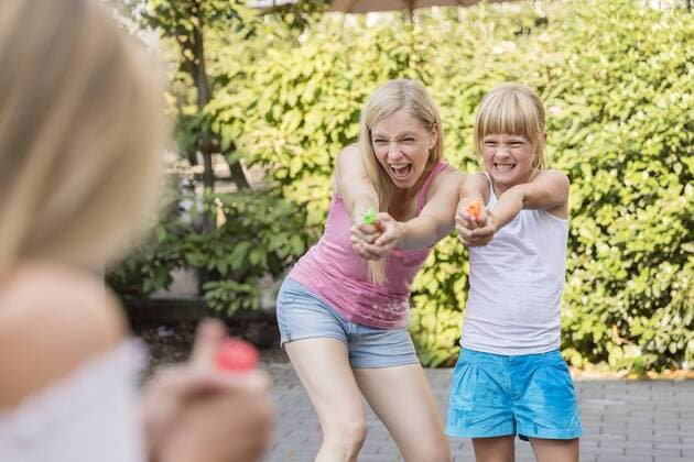 Mother and two girls splashing with water guns in garden model released Symbolfoto  SHKF00807