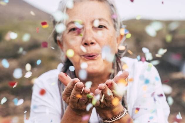Senior woman blowing confetti outdoors model released Symbolfoto  SIPF01976