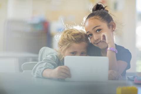 IMAGO Creative: NGO, Ausbildung für Kinder Portrait of two smiling girls sharing mini tablet in kindergarten model released Symbolfoto property released  ZEF15461