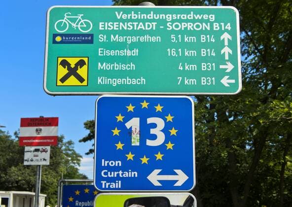 Wegweiser auf dem Radweg Iron Curtain Trail entlang der Grenze zwischen Ungarn und Österreich nahe dem Grenzübergang bei Fertörakos, Ungarn, und Sankt Margarethen, Österreich *** Directional sign on the bike tour Irin Curtain Trail along the border between Hungary and Austria near the border crossing between Fertörakos, Hungary, and Sankt Margarethen, Austria