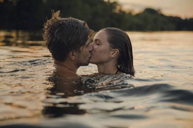 Young couple swimming in lake, kissing at sunset model released Symbolfoto  GUSF02361