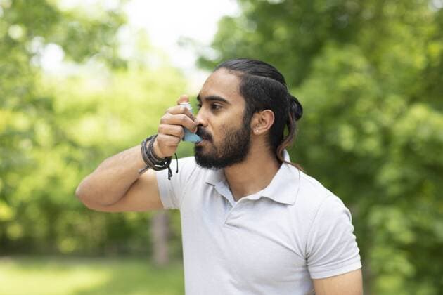 Young man in nature using asthma inhaler model released Symbolfoto  SGF02376