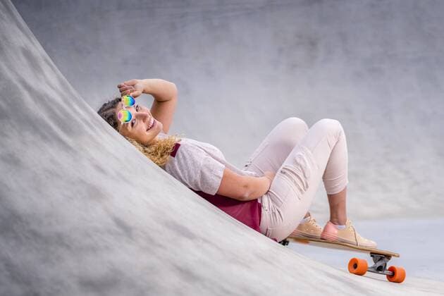 Smiling young woman with a longboard at a skatepark model released Symbolfoto  STSF02046