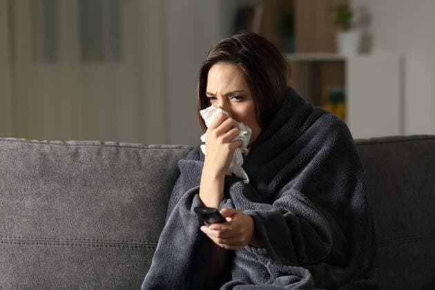  Ill woman blowing and watching tv at home ,model released, Symbolfoto  Copyright: xAntonioGuillemx Panthermedia26592354