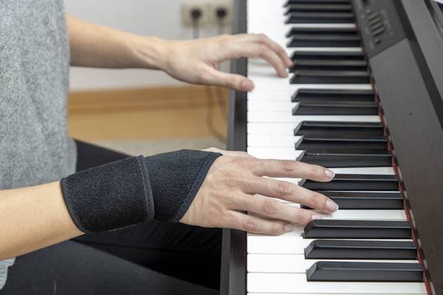 Symbolbild Sehnenscheidenentzündung, Frau mit Handgelenkbandage, Klavier *** symbol picture tendosynovitis, woman with wrist bandage, piano
