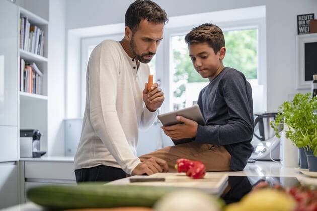 Father and son using tablet and cooking in kitchen at home together model released Symbolfoto property released  DIGF07774