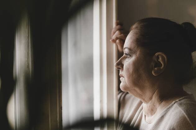 Serious senior woman looking out of window at home model released Symbolfoto property released  GUSF02222