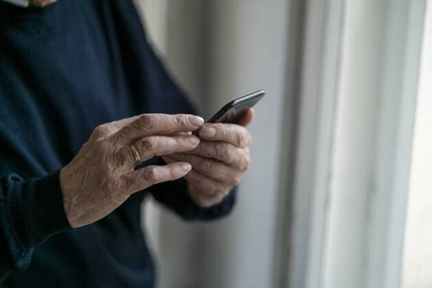 Close-up of senior man using cell phone at home model released Symbolfoto property released  GUSF02240