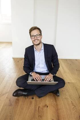 Portrait of a smiling businessman sitting on the floor using laptop model released Symbolfoto property released  PESF01697