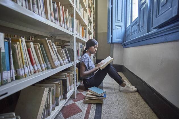 Young woman sitting on the floor reading a book at National library, Maputo, Mocambique model released Symbolfoto property released  VEGF00393