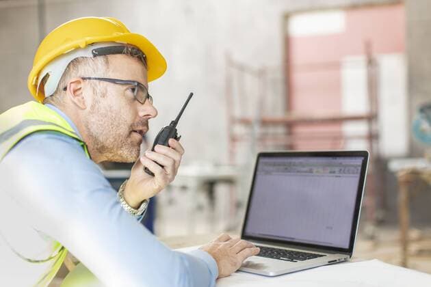Architect using laptop and walkie talkie at construction site model released Symbolfoto property released  ZEF16154