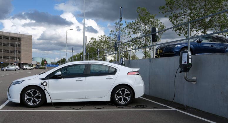 A car electric car with electric drive of the type Opel Ampera E is charged with electricity at a charging station on the parking lot in the Outletcenter in Roermond A car electric car with electric drive of the type Opel Ampera E is charged with electricity at a charging station on the parking lot in the Outletcenter in Roermond