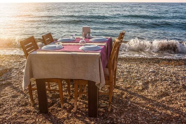 Table set for four people with chairs of an outdoor restaurant on the shore of the sea in a holiday resort in Turkey Kusadasi, Turkey