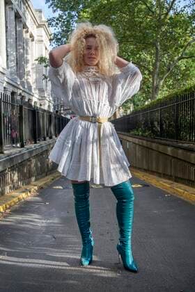 Street Style on day three of London Fashion Week SS 2020 on Saturday September 14th 2019, showcasing stylish individuals London is internationally known for. Image shows Angel from Manchester. She wears over the knee boots by Elisabetta Franchi, a white lace dress by Three People, a Vivienne Westwood necklace and a yellow Burberry belt  (112123953)