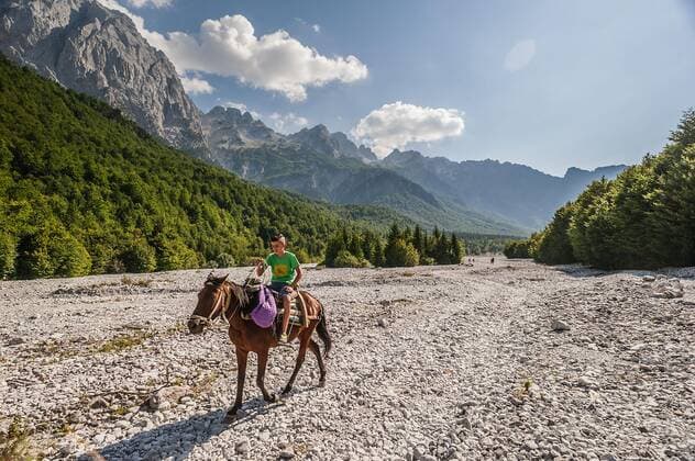 Ein Reiter mit Pferd reitet auf einem Schotterweg, der durch das im Sommer ausgetrocknete Flussbett der Valbona bergauf Richtung Theth führt. Valbona (ValbonÃ«), KukÃ«s, Albanien. Mit dem Campingbus unterwegs in Albanien *** A rider with a horse rides on a gravel path that leads uphill through the dry riverbed of the Valbona in summer towards the Theth Valbona ValbonÃ , KukÃ s, Albania On the road in Albania with the camping bus