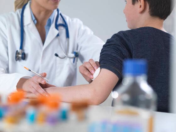 Female doctor giving a boy a routine vaccination in the clinic model released Symbolfoto property released  ABRF00624