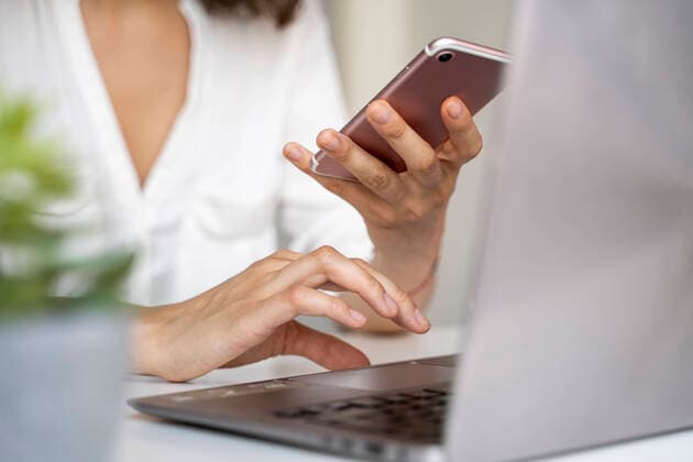 Close-up of woman using cell phone and laptop at desk model released Symbolfoto property released  AFVF03714