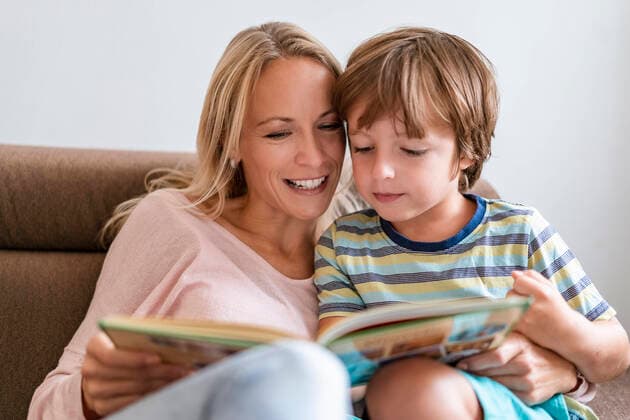 Mother and son reading a book together on couch at home model released Symbolfoto property released  DIGF08133