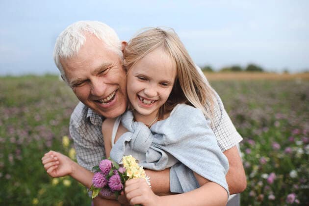 Portrait of happy grandfather and granddaughter with picked flowers on a meadow model released Symbolfoto  EYAF00425