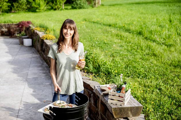 Portrait of smiling woman preparing food on barbecue grill model released Symbolfoto property released  FMKF05792
