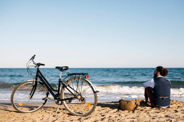 Well dressed man with his bike sitting on a beach model released Symbolfoto  JRFF03628