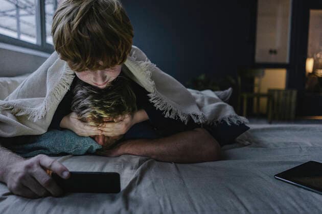 IMAGO Creative, Gesellschaft, Immer mehr Menschen haben Angst vor der Zukunft Father and son lying together under blanket using smartphone model released Symbolfoto property released  KNSF06294