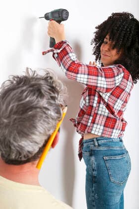 Couple drilling hole in the wall at home model released Symbolfoto property released  RTBF01345