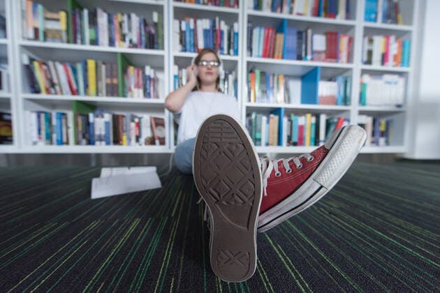 female student study in library using tablet and searching internet while Listening music and lessons on white headphones,model released, Symbolfoto ING_32193_111978