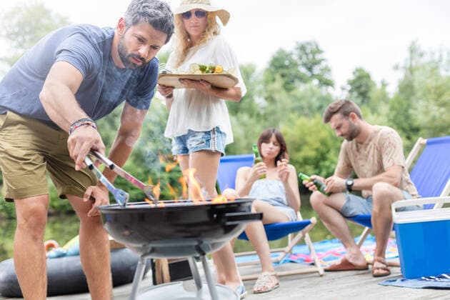 Man preparing food in barbecue grill with friends on pier,model released, Symbolfoto INH_19064_11879
