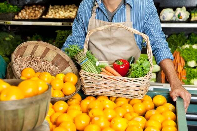 Midsection of man standing near oranges stall with vegetable basket in supermarket,model released, Symbolfoto,property released 03B91320