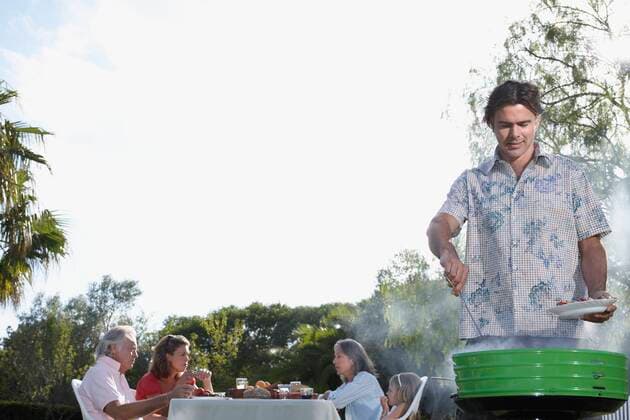Man grilling, people sitting at table in background,model released, Symbolfoto,property released 03C03724