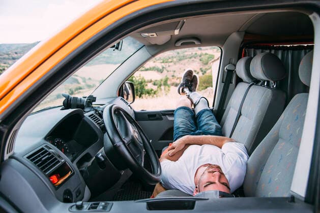 Young man with leg prosthesis resting in camper van model released Symbolfoto  CJMF00024