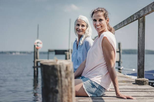 Mother and daughter sitting on jetty, relaxing at the sea model released Symbolfoto  JOSF03708