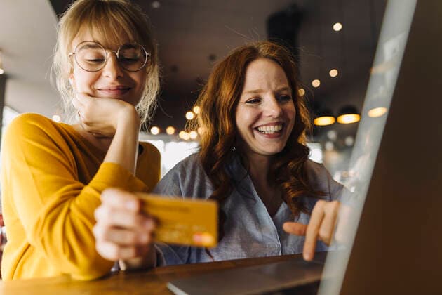 Two happy female friends with laptop and credit card in a cafe model released Symbolfoto property released  KNSF06709