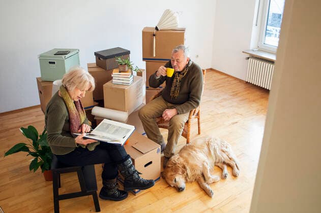Senior couple having a break surrounded by cardboard boxes in an empty room model released Symbolfoto property released  MAMF00819