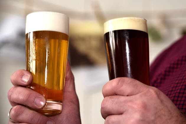 Two hands each holding a beer glass with Pils and one with top-fermented beer against a blurred background Two beer glasses with light and dark beer, Schwerte North Rhine-Westphalia Germany
